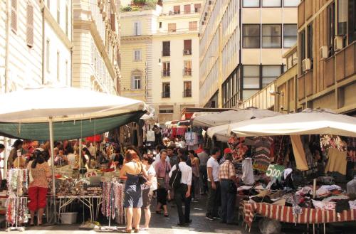 una folla di persone che camminano per un mercato in una città di Hotel Corona a Roma