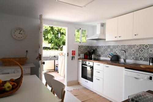 a kitchen with white cabinets and a table with fruits on the counter at Casa dos Clérigos in Alcácer do Sal