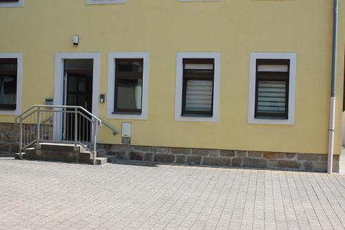 a yellow building with windows and a staircase in front at Ferienoase Kleine Perle in Pirna