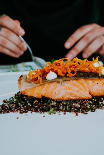 a person eating a piece of fish on a plate at Pefkaki Boutique Hotel Loutraki in Loutraki