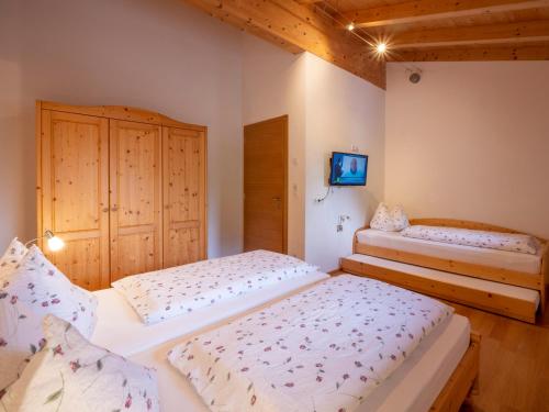 a bedroom with two beds and a tv on the wall at Huberhof Mareit - Südtirol in Racines