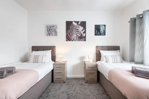 two beds in a bedroom with pictures on the wall at Ideal location in Morriston! in Swansea