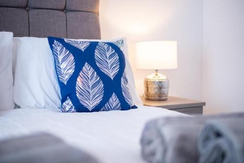 a bed with a blue and white pillow and a lamp at Spacious 3BR Home with Parking in Swansea in Swansea