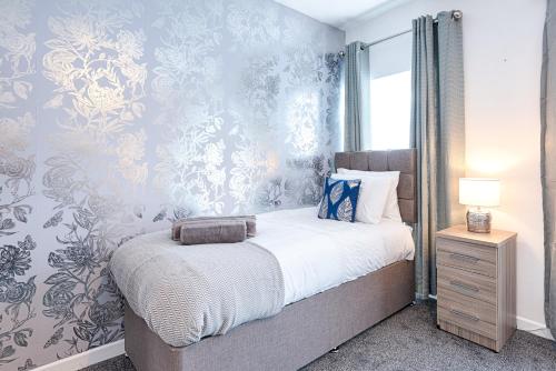 a bedroom with a bed with blue and silver wallpaper at Spacious 3BR Home with Parking in Swansea in Swansea
