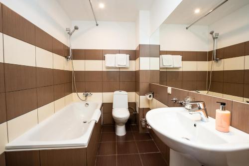 a bathroom with two sinks and a tub and a toilet at Primo Hotel in Rīga