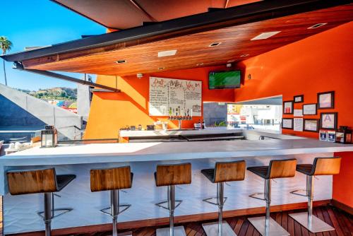 a bar in a restaurant with orange walls and stools at The Moment Hotel in Los Angeles