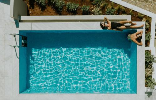 two people laying in a swimming pool at Pefkaki Boutique Hotel Loutraki in Loutraki