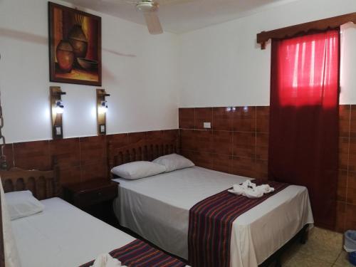 a room with two beds and a red window at Hotel La Union in Flores