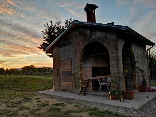 Agriturismo "La Fondazza" في إيمولا: منزل كلب من الطوب صغير عليه كرسي