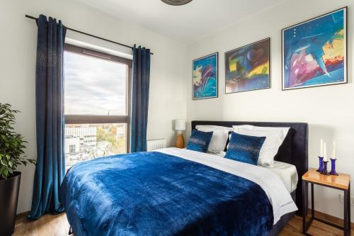 a bedroom with a blue and white bed and a window at Glamour Apartment City View in Wrocław