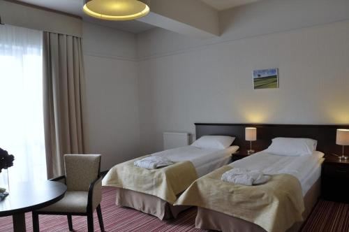 a hotel room with two beds and a table and chair at Radocza Park Active & Spa in Radocza