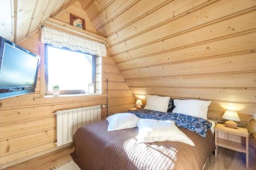 a bedroom with a bed in a wooden room at Willa w Ubocy - "Jacuzzi i Sauna w ofercie dodatkowo płatnej" in Murzasichle