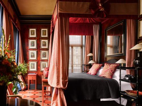 a bedroom with a bed with red curtains and a window at Blakes Hotel in London