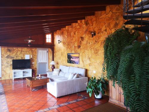 a living room with a couch and a stone wall at Camino Real in Barranco Hondo
