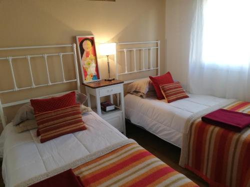 1 dormitorio con 2 camas y mesa con lámpara en Alojamiento familiar en Coronel Suárez