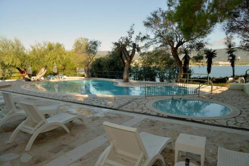 a swimming pool with chairs and a table at Saint Nicholas Beach Resort in Dassia
