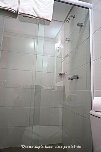 a bathroom with a shower with a glass door at Pousada Molhes da Barra in Torres