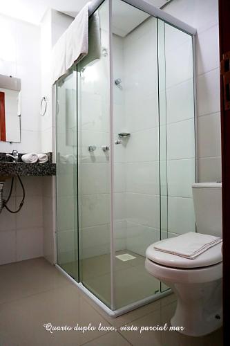 a glass shower in a bathroom with a toilet at Pousada Molhes da Barra in Torres