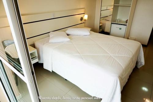 a bedroom with a white bed and a mirror at Pousada Molhes da Barra in Torres