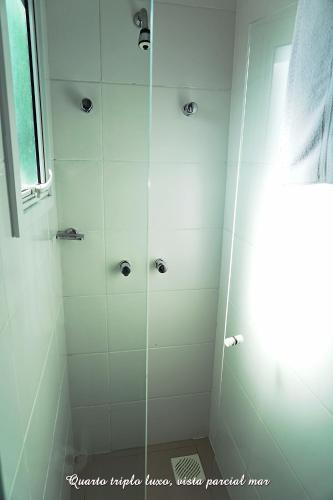 a bathroom with a shower with white tile at Pousada Molhes da Barra in Torres