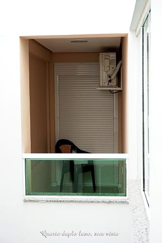 a glass table in a window with a chair at Pousada Molhes da Barra in Torres