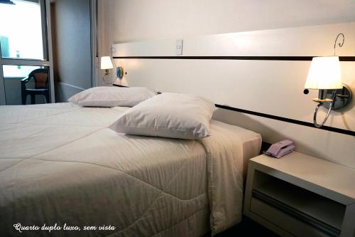 two beds in a hotel room with a phone on a table at Pousada Molhes da Barra in Torres