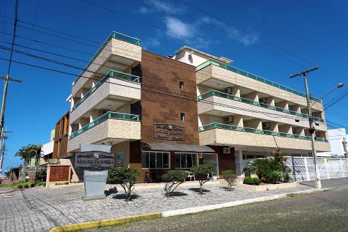 a building on a street with trees in front of it at Pousada Molhes da Barra in Torres