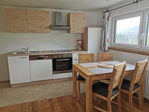 eine Küche mit einem Tisch, Stühlen und einem Waschbecken in der Unterkunft Biohof Gölly in Neumarkt in Steiermark