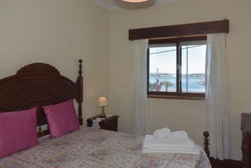 a bedroom with a bed with purple pillows and a window at L'ALCIBÍADES - Costa Nova in Costa Nova