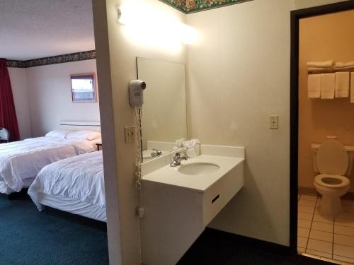 a bathroom with a sink and a bed and a toilet at TravelStar Inn & Suites in Colorado Springs
