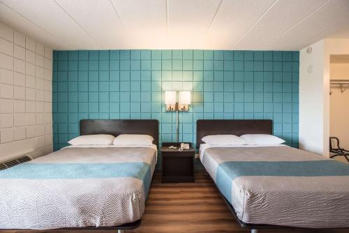 two beds in a room with blue tiled walls at Motel 6-Somers Point, NJ - Ocean City - Wild Wood Beach in Somers Point