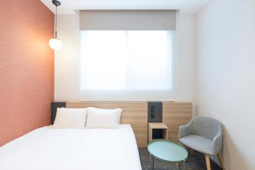 a bedroom with a bed and a chair at M's Hotel Sanjo Omiya in Kyoto