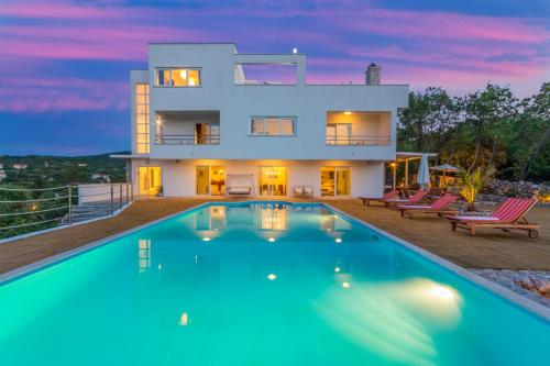 a house with a swimming pool in front of it at Villa Vrbnik in Vrbnik