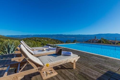 a villa with a swimming pool and a lounge chair at Villa Vrbnik in Vrbnik