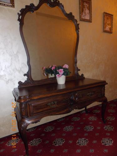 a dresser with a mirror and a vase of flowers on it at Vila Royal in Bacău