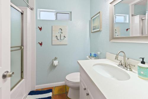 ein Badezimmer mit einem Waschbecken, einem WC und einem Spiegel in der Unterkunft Luna Azul, cozy condo only steps to Mission Beach! Free Internet in San Diego
