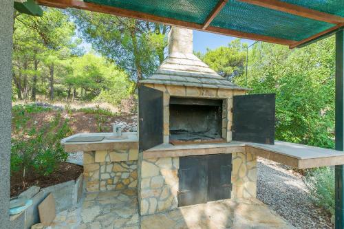 an outdoor pizza oven in a yard with trees at Apartment Ametist in Milna