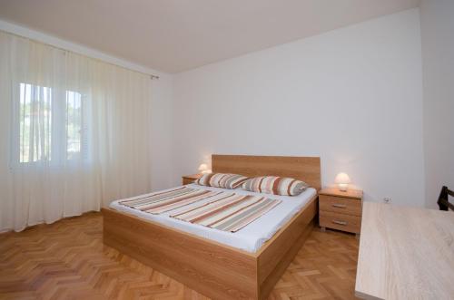 a white bedroom with a bed and a window at Apartment Ruza in Lopar