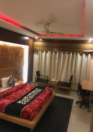 a bedroom with a bed with a red comforter at Citi Club in Kānpur