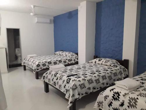 a room with three beds and a blue wall at HOTEL TANIA in Caucasia