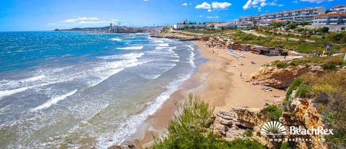 a beach with people laying on the sand and the water at Sitges Holiday Apartment in Sitges