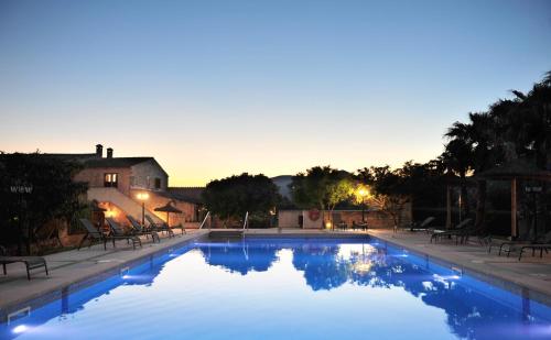 a large swimming pool with blue water at dusk at Finca Ses Cases Noves in Sant Llorenç des Cardassar