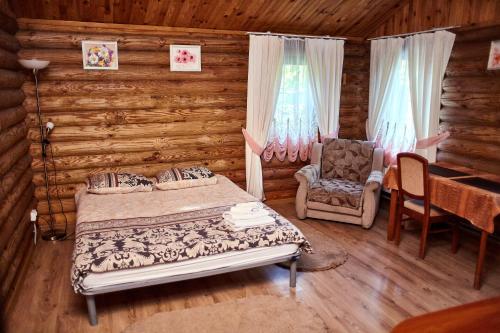 sypialnia z łóżkiem i krzesłem w drewnianym domku w obiekcie Zolotoy Bereg Hotel w mieście Czernihów