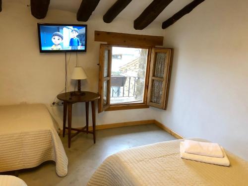 a bedroom with two beds and a television on the wall at Solano de Moran in Murillo de Gállego