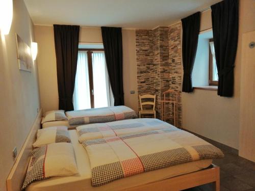 a bedroom with two beds and a stone wall at Agriturismo Al Palaz in Prata Camportaccio