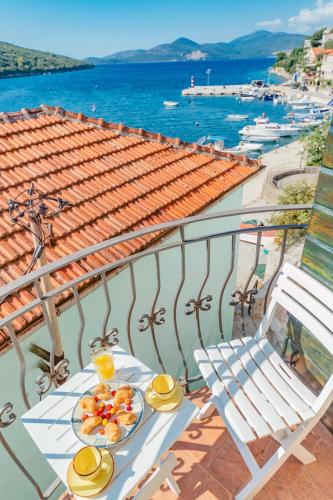 a table with plates of food and a chair on a balcony at Apartments Bigovo Veljic in Tivat