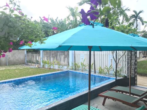 a blue umbrella sitting next to a swimming pool at The Moon River Homestay & Villa in Hoi An