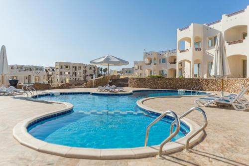 a swimming pool with chairs and buildings in the background at Sharks Bay apartments for rent in Sharm El Sheikh