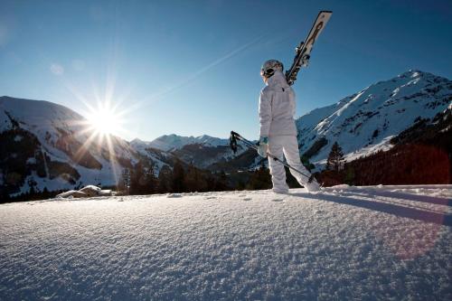 a person standing on a snow covered slope holding skis at Alpen Appartements Lärchenhof in Lermoos