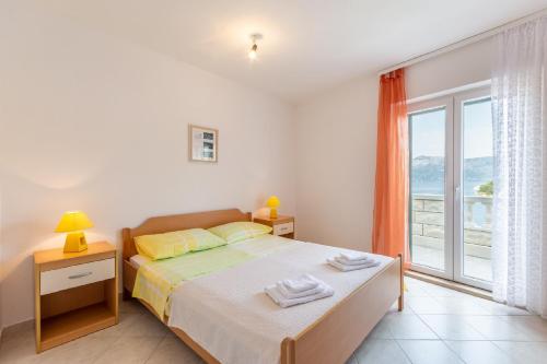a bedroom with a bed and a large window at Apartments Darija in Pučišća